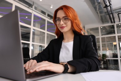 Photo of Woman working with laptop at white desk in office