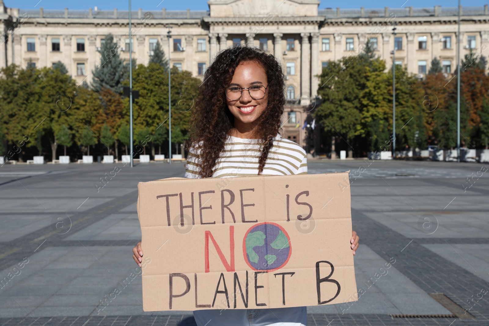 Photo of African American young woman with poster protesting against climate change on city street