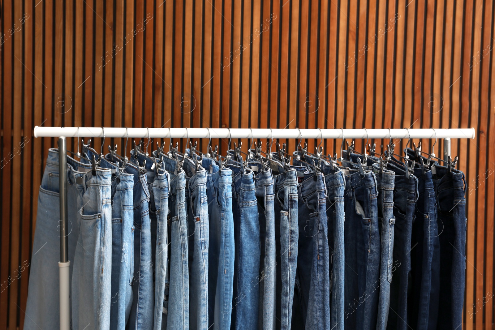 Photo of Rack with different jeans on wooden background