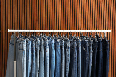 Photo of Rack with different jeans on wooden background