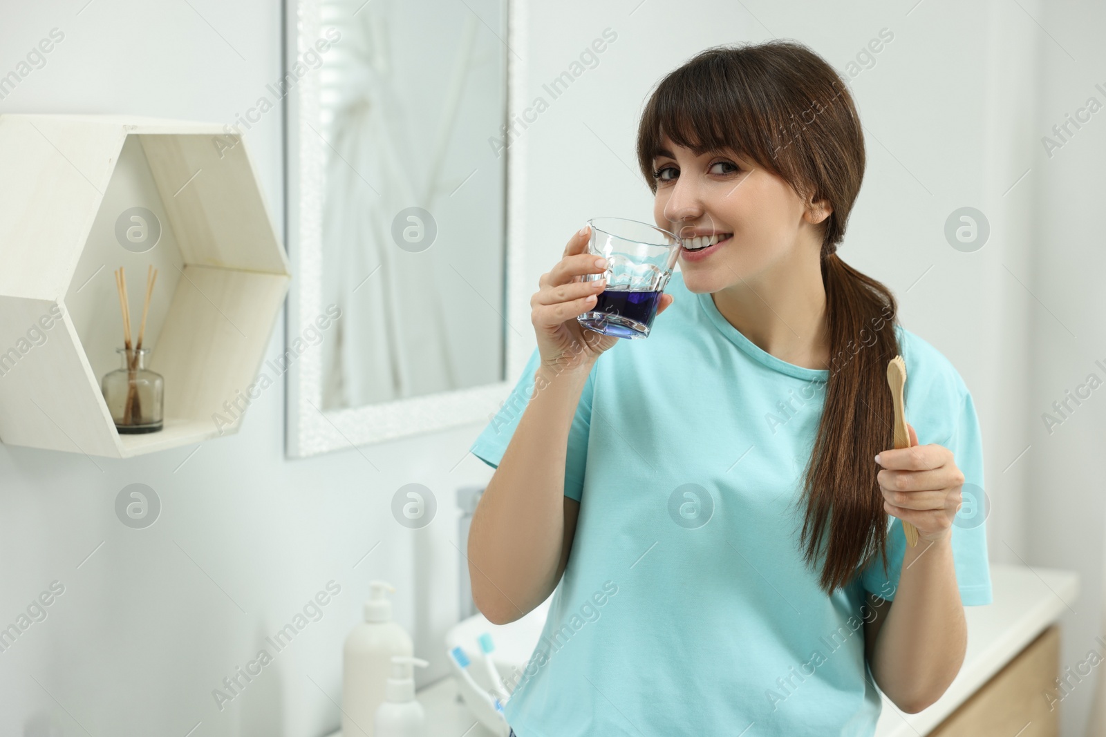 Photo of Young woman using mouthwash in bathroom. Oral hygiene