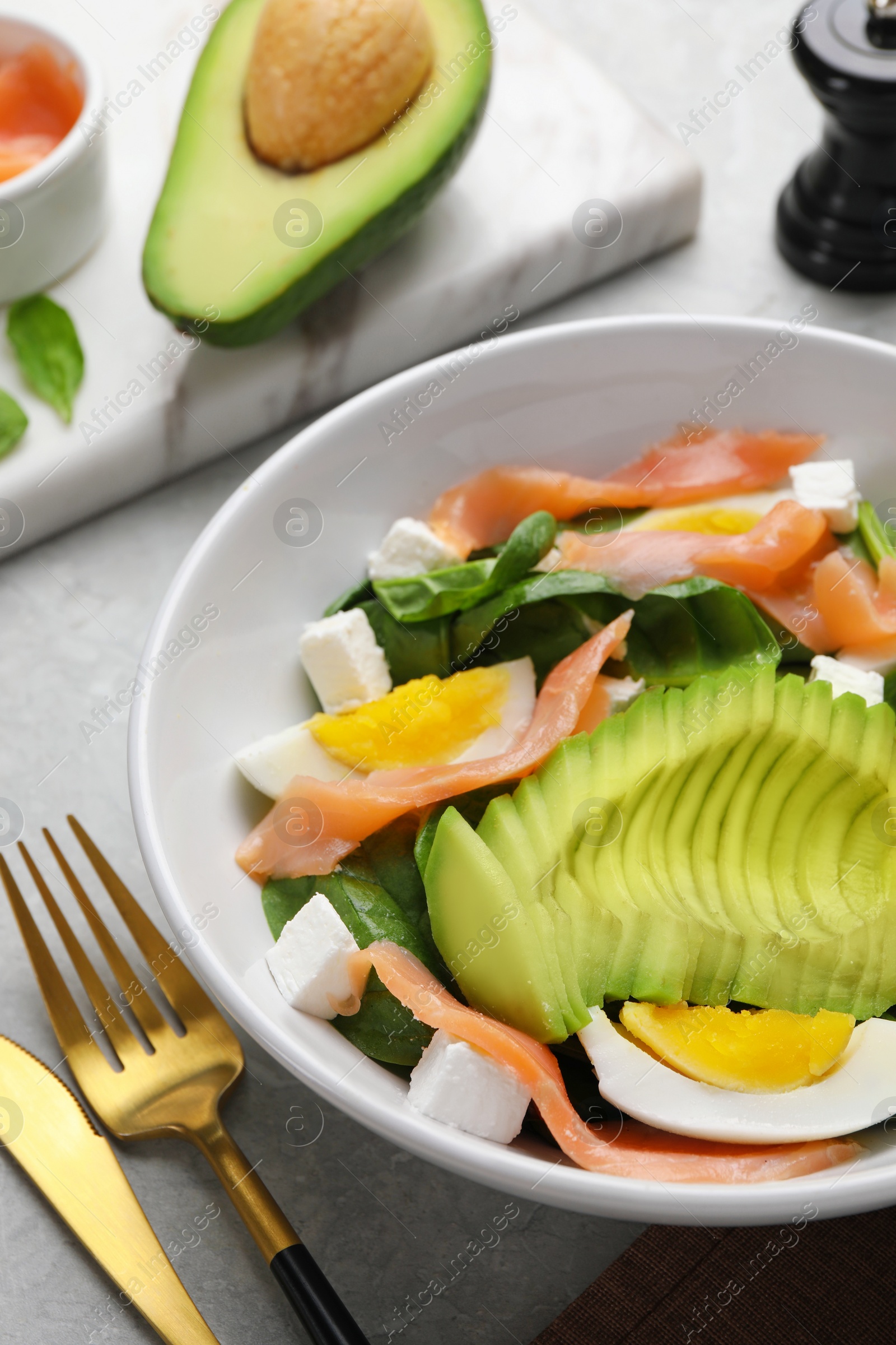 Photo of Delicious salad with boiled egg, salmon and avocado served on light grey table, closeup