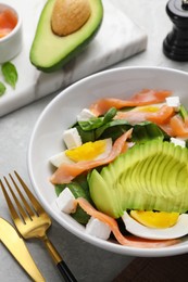 Photo of Delicious salad with boiled egg, salmon and avocado served on light grey table, closeup