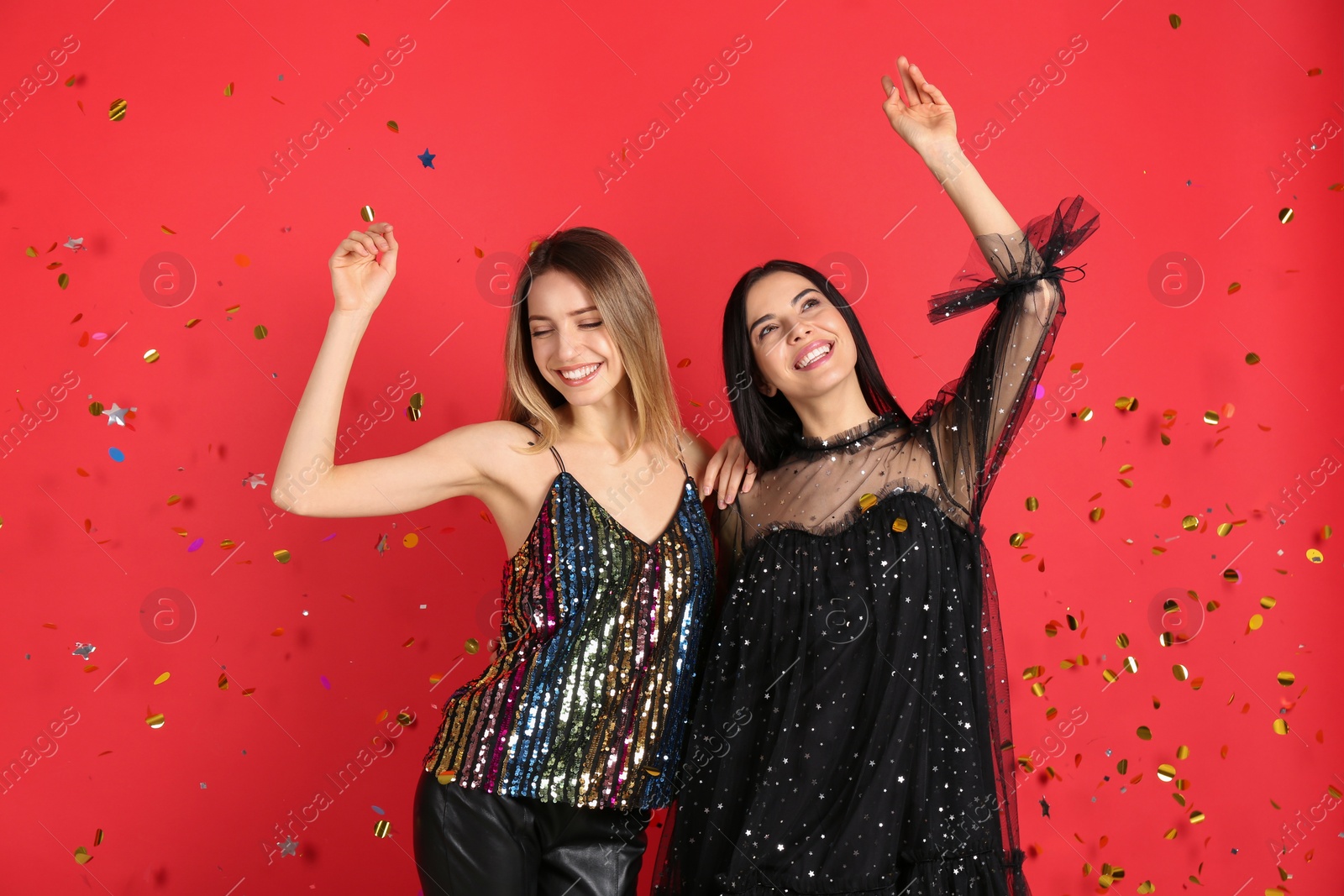 Photo of Happy women and falling confetti on red background