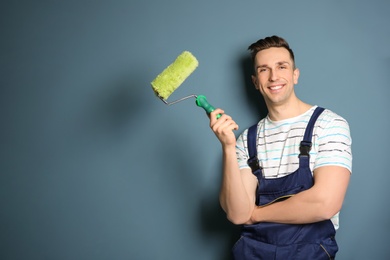 Photo of Young male decorator with paint roller near color wall