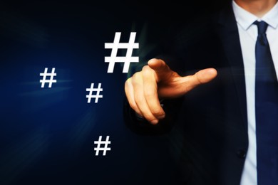 Image of Hashtag concept. Man pointing at sign on dark blue background, closeup