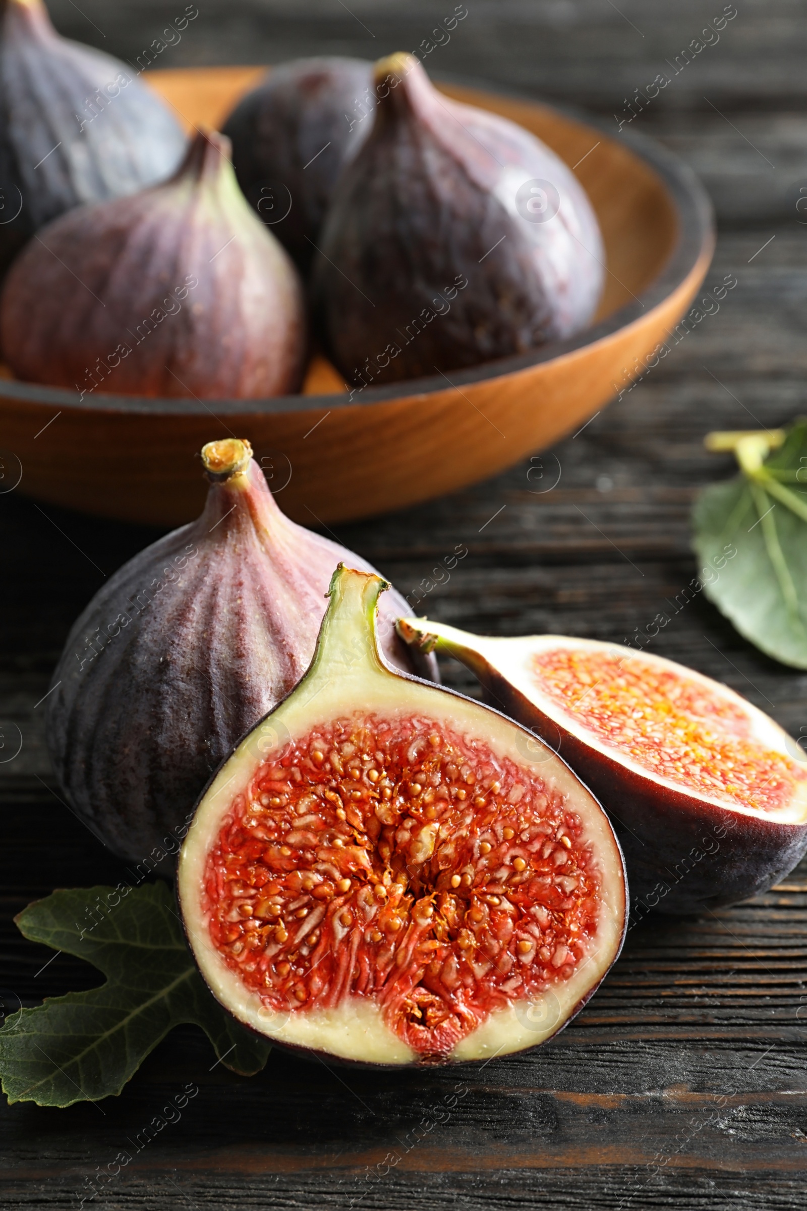 Photo of Fresh ripe figs with leaves on wooden table. Tropical fruit