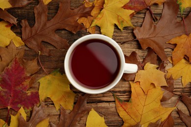 Cup of hot tea and autumn leaves on wooden table, flat lay