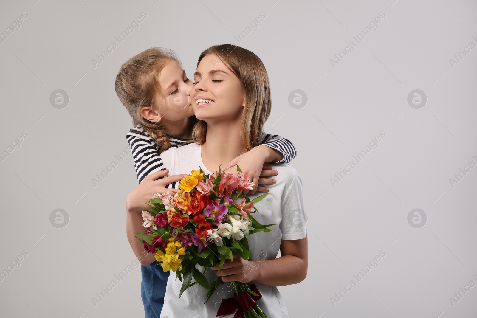 Photo of Little daughter congratulating her mom with flowers on white background. Happy Mother's Day