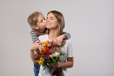 Photo of Little daughter congratulating her mom with flowers on white background. Happy Mother's Day