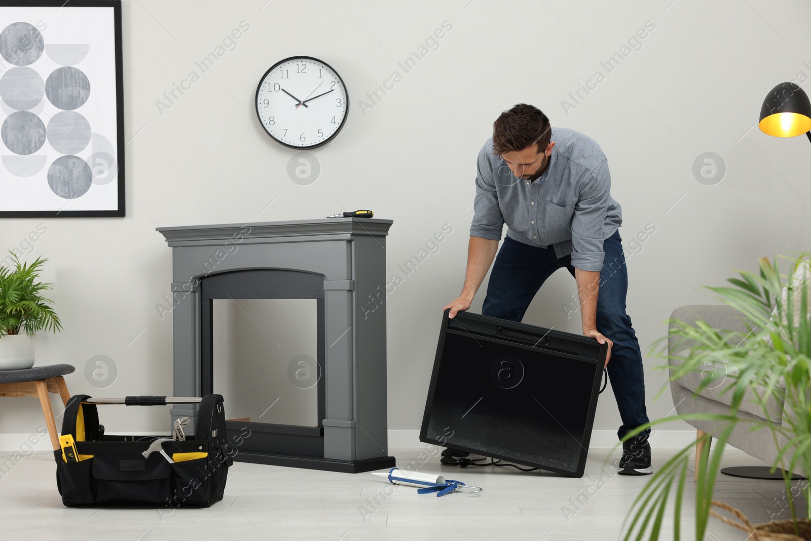 Photo of Man installing electric fireplace near wall in room