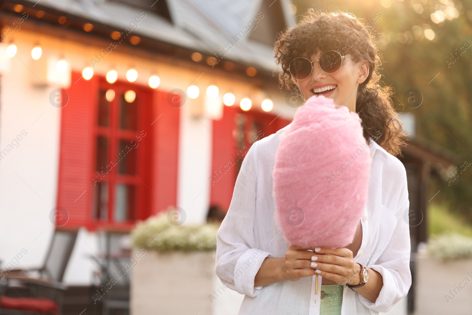 Photo of Smiling woman with cotton candy outdoors on sunny day. Space for text