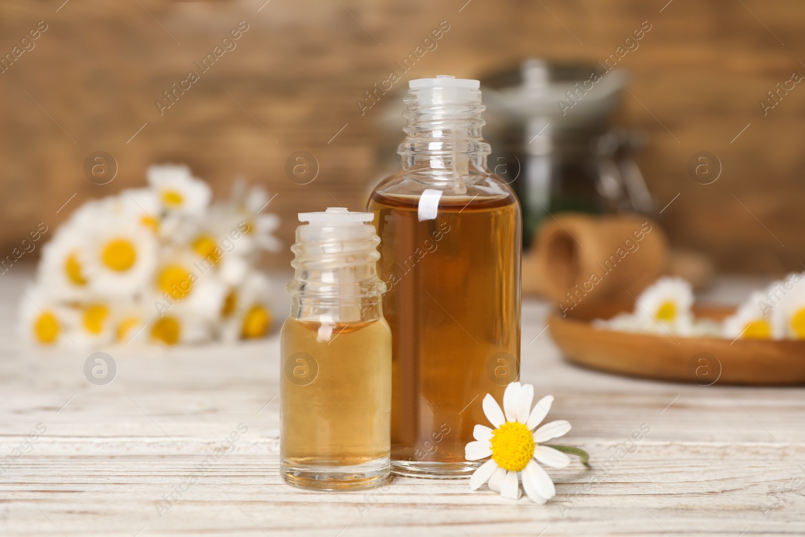 Photo of Composition with bottles of chamomile essential oil on table