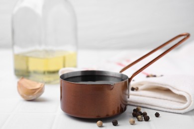 Photo of Metal small saucepan with balsamic vinegar and ingredients on white table