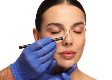 Image of Woman preparing for cosmetic surgery, white background. Doctor drawing markings on her face, closeup