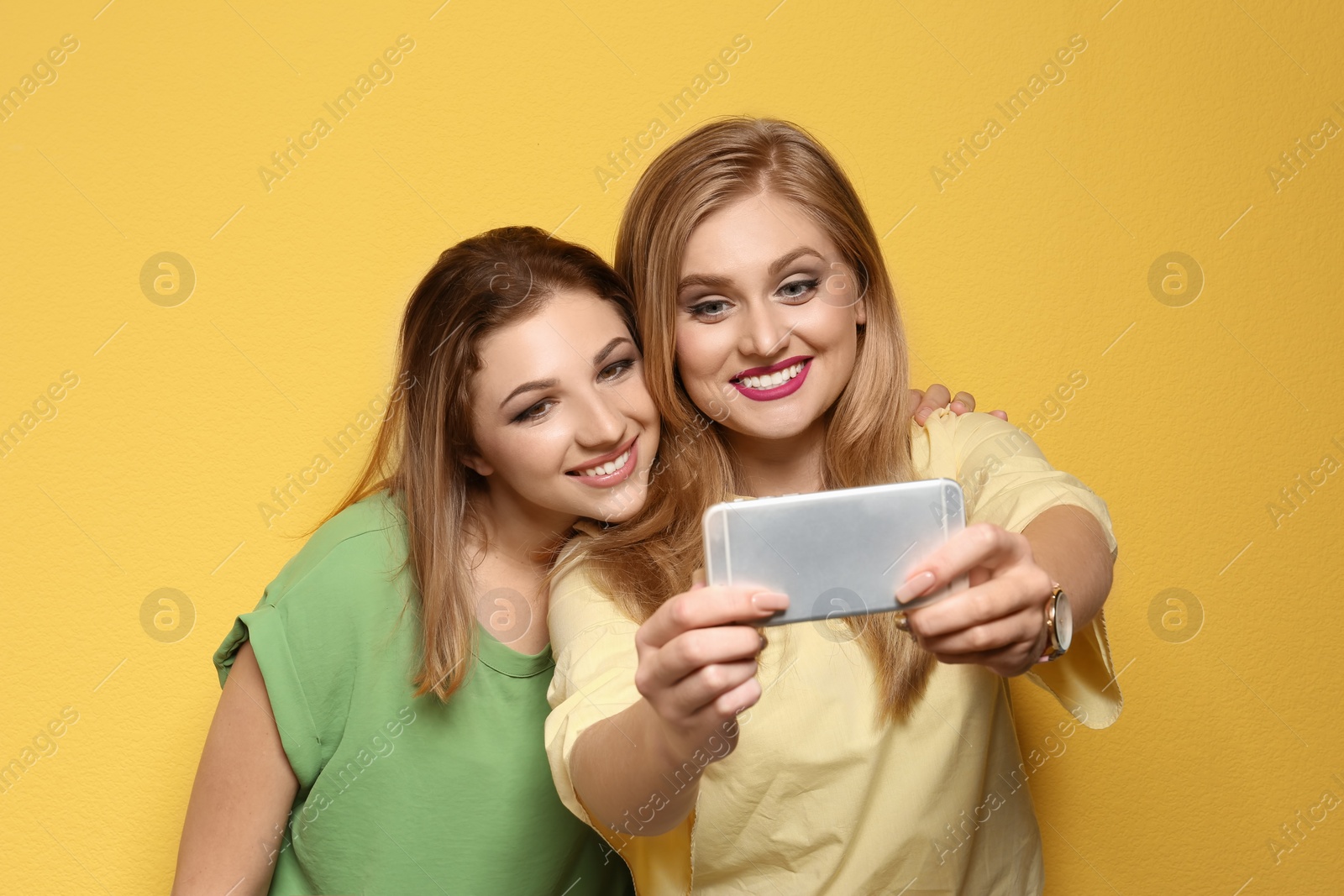 Photo of Attractive young women taking selfie on color background