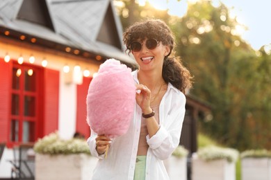 Portrait of smiling woman with cotton candy outdoors on sunny day