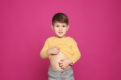 Photo of Little boy scratching belly on color background. Annoying itch