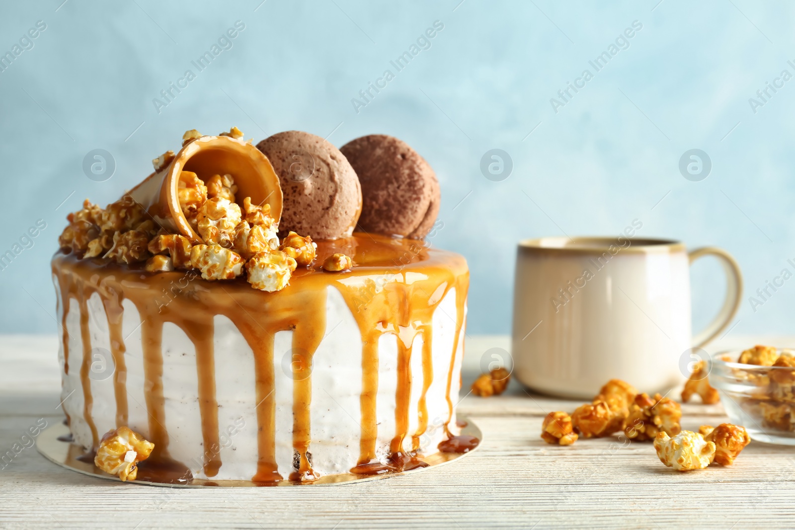 Photo of Delicious homemade cake with caramel sauce and popcorn on table