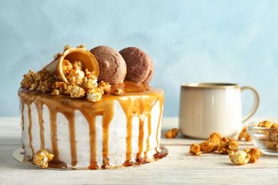 Delicious homemade cake with caramel sauce and popcorn on table