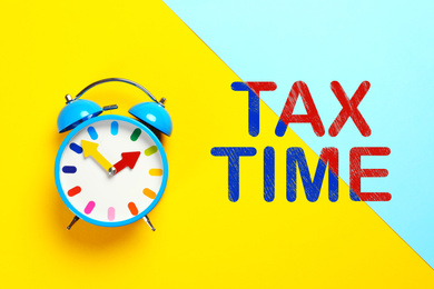 Image of Time to pay taxes. Alarm clock on color background, top view