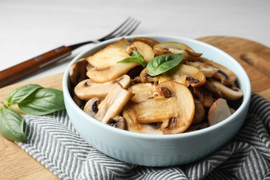 Delicious cooked mushrooms with basil served on table