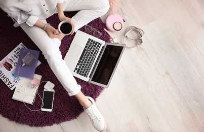 Photo of Female blogger with laptop and cup of coffee indoors, top view