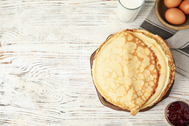 Photo of Flat lay composition with fresh thin pancakes on white wooden table. Space for text