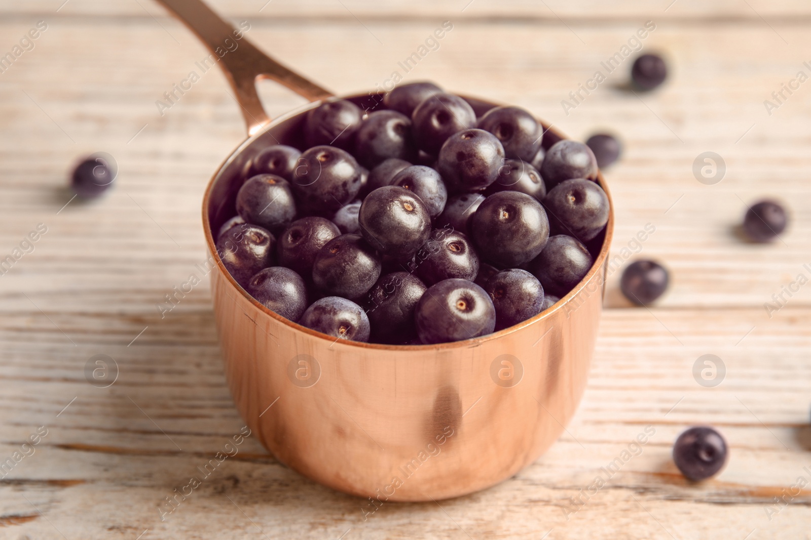 Photo of Dish with fresh acai berries on wooden table, closeup