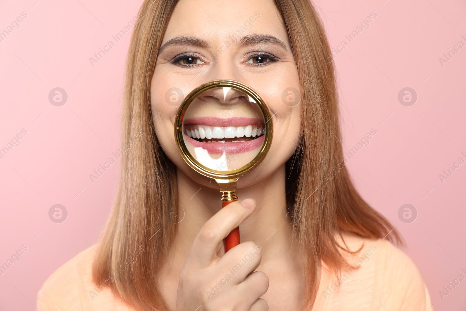 Photo of Smiling woman with perfect teeth and magnifier on color background, closeup