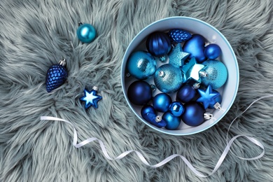 Photo of Beautiful Christmas baubles and box on grey faux fur, flat lay