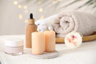 Photo of Spa composition. Burning candles and personal care products on soft white surface