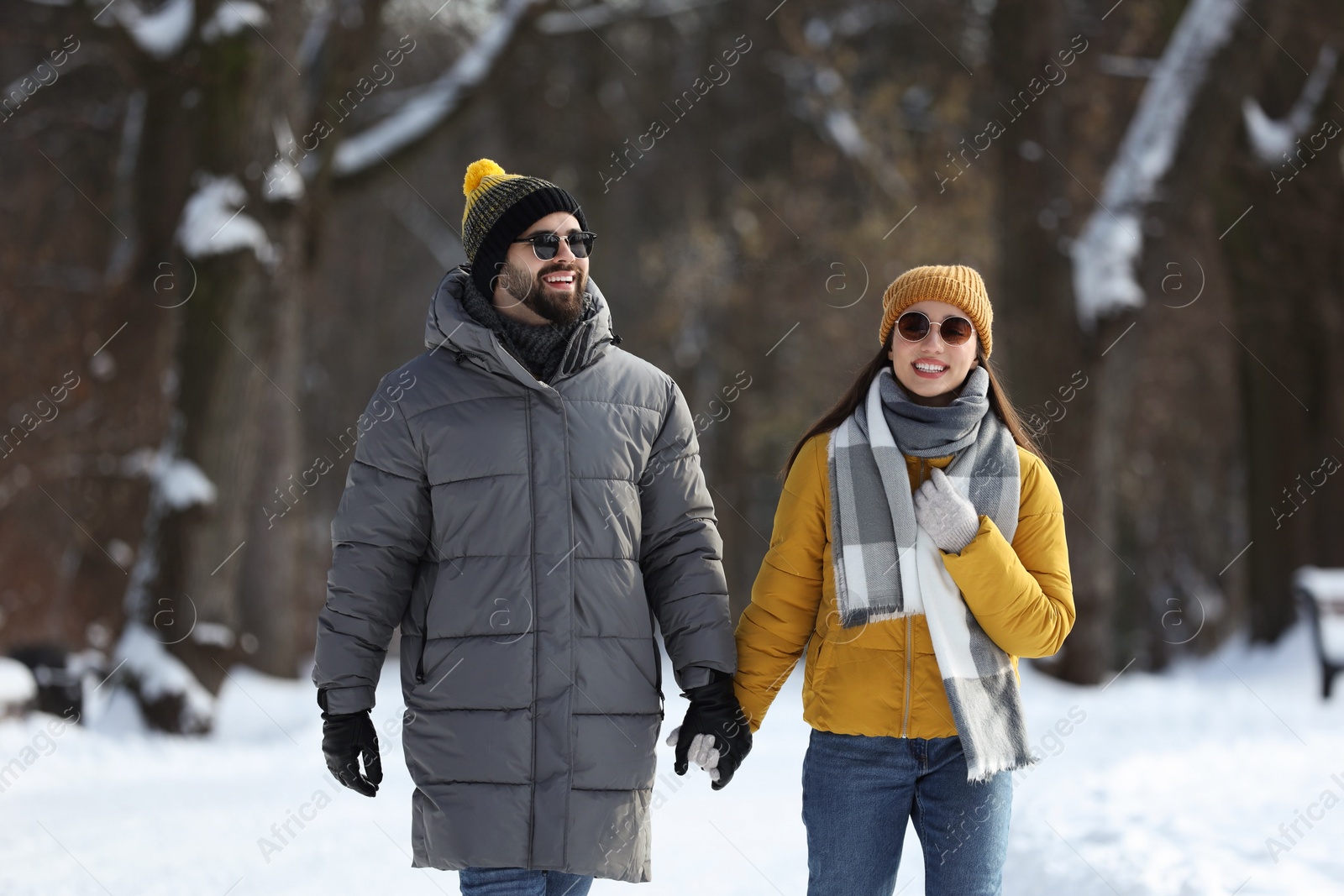 Photo of Happy young couple walking in snowy park on winter day