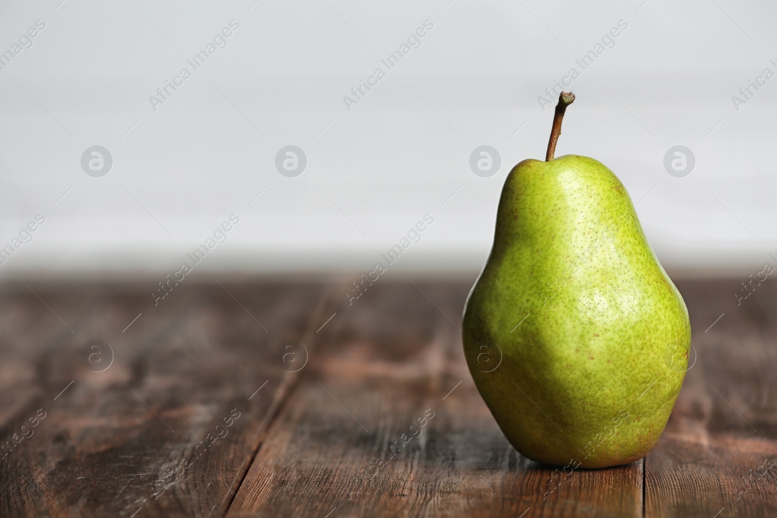 Photo of Ripe pear on wooden table against blurred background. Space for text