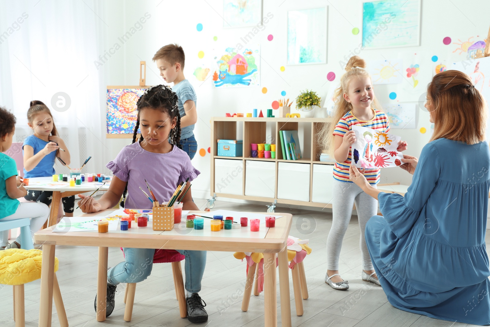 Photo of Children with female teacher at painting lesson indoors