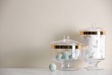 Jars with cotton pads and bath bombs on table against beige background. Space for text