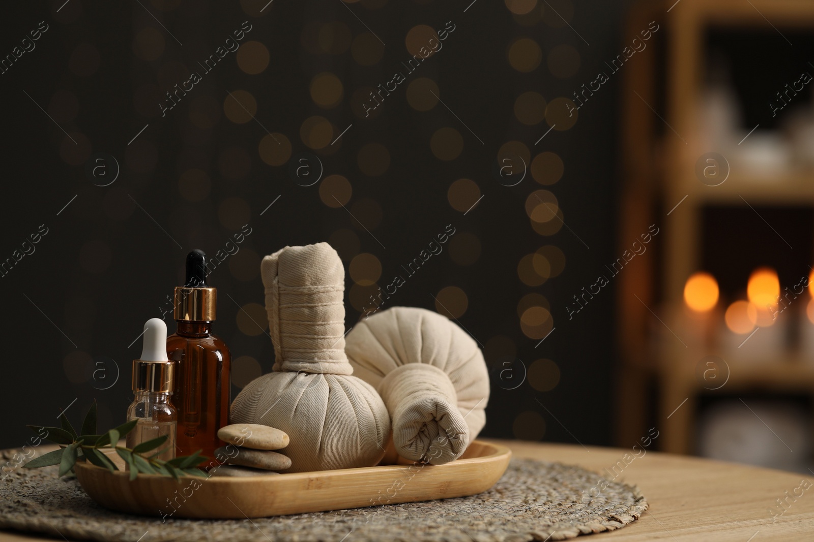 Photo of Spa composition. Herbal sacks, cosmetic products and stones on table indoors. Space for text