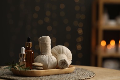 Spa composition. Herbal sacks, cosmetic products and stones on table indoors. Space for text