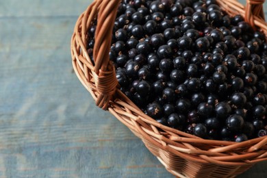 Ripe blackcurrants in wicker basket on wooden rustic table, closeup. Space for text