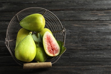 Fresh ripe figs in basket on wooden table, top view. Space for text