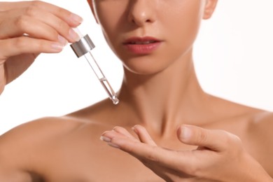 Woman applying cosmetic serum onto her hand on white background, closeup