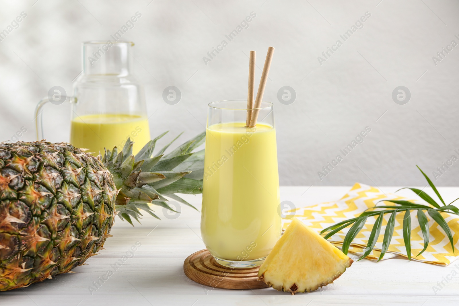 Photo of Tasty pineapple smoothie and fruit on white wooden table