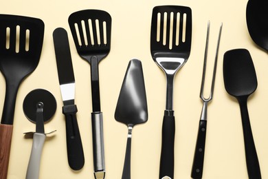 Photo of Different spatulas and other kitchen utensils on beige background, flat lay