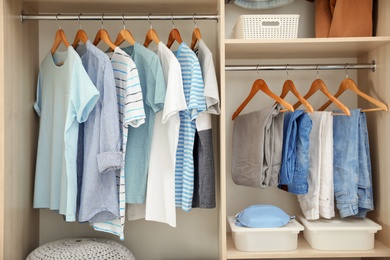 Photo of Stylish clothes on hangers in wardrobe closet