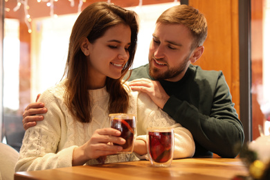 Photo of Couple with tasty mulled wine at table in cafe. Winter vacation