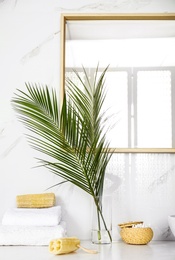 Photo of Tropical palm leaves in stylish bathroom interior