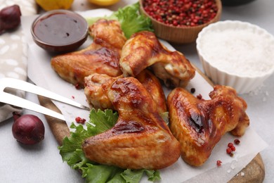 Photo of Fresh marinated chicken wings, spices and lettuce on light table, closeup