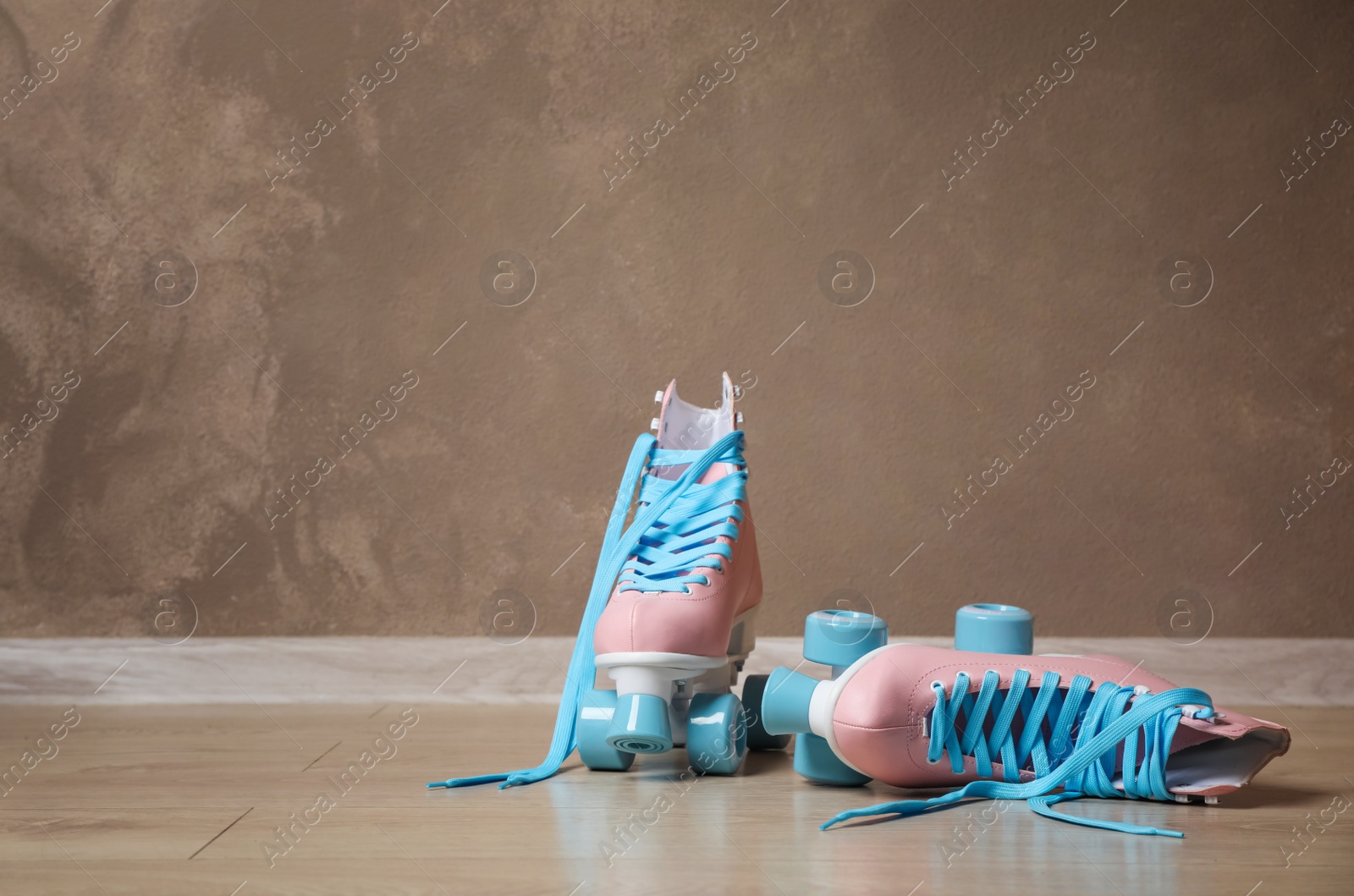 Photo of Vintage roller skates on floor near brown wall. Space for text