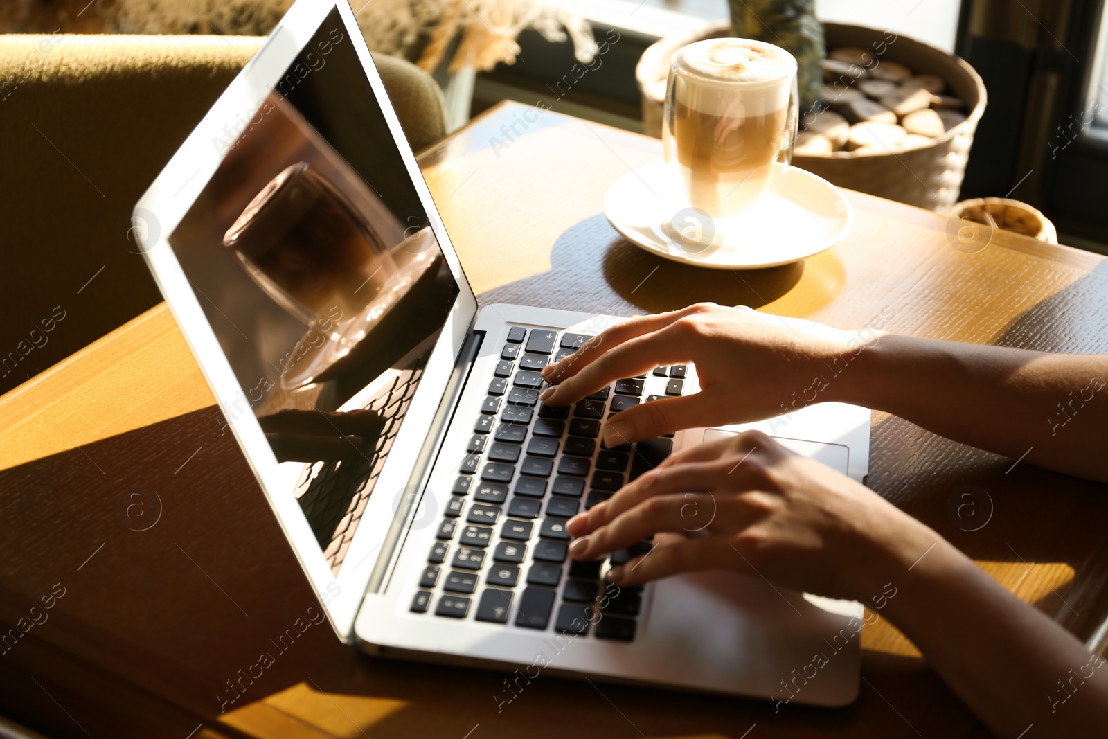 Photo of Woman using laptop at table, closeup of hands