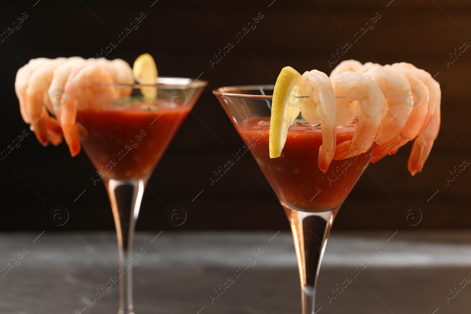 Photo of Tasty shrimp cocktail with sauce in glasses and lemon on grey table, closeup